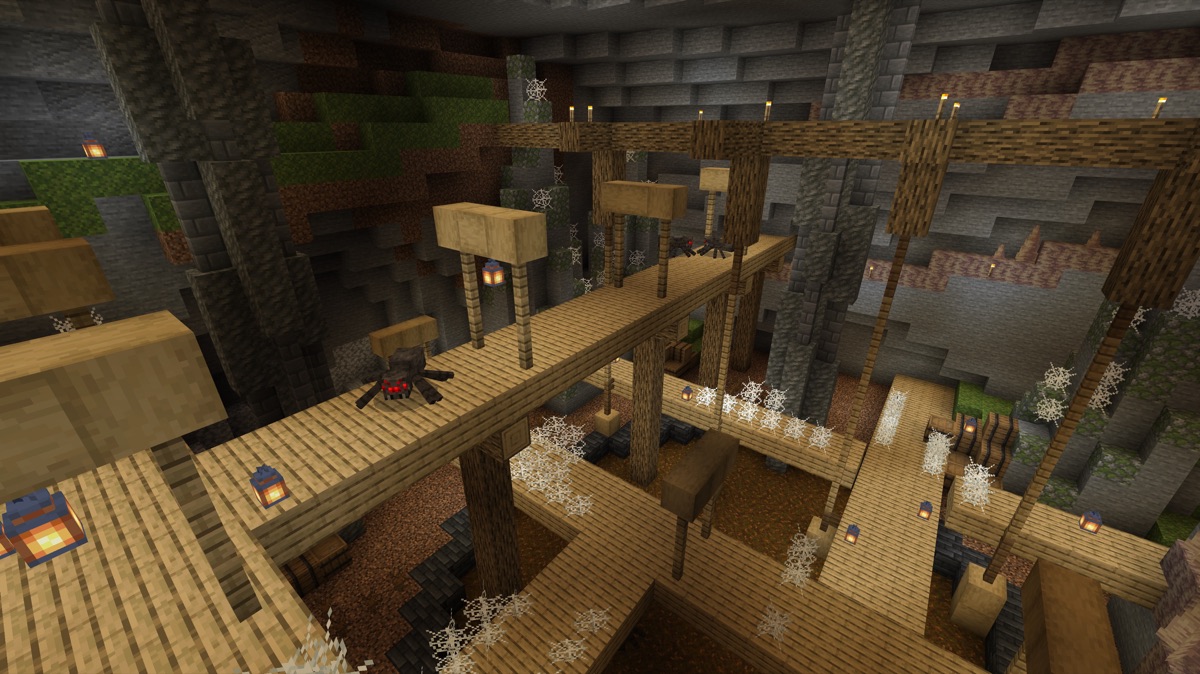 Wooden walkways cross a deep cave filled with cobwebs and spiders.