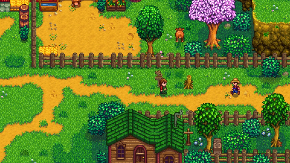 A farmer works outside among crops and fruit trees.